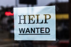 A "Help Wanted" sign hanging on the window of a business.